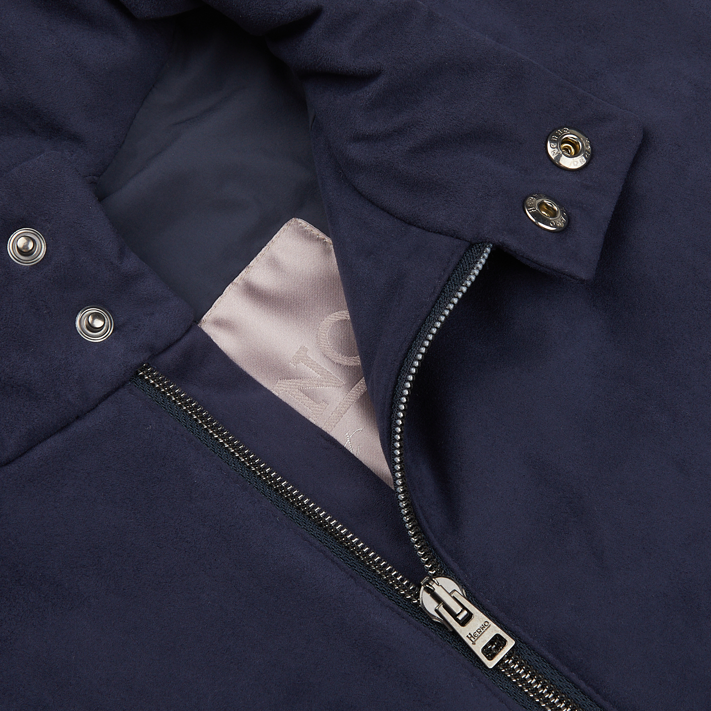 Close-up of a Herno navy blue suede Alcantara Zip Gilet showing a partially unzipped zipper, metal snap buttons, and an interior tag.