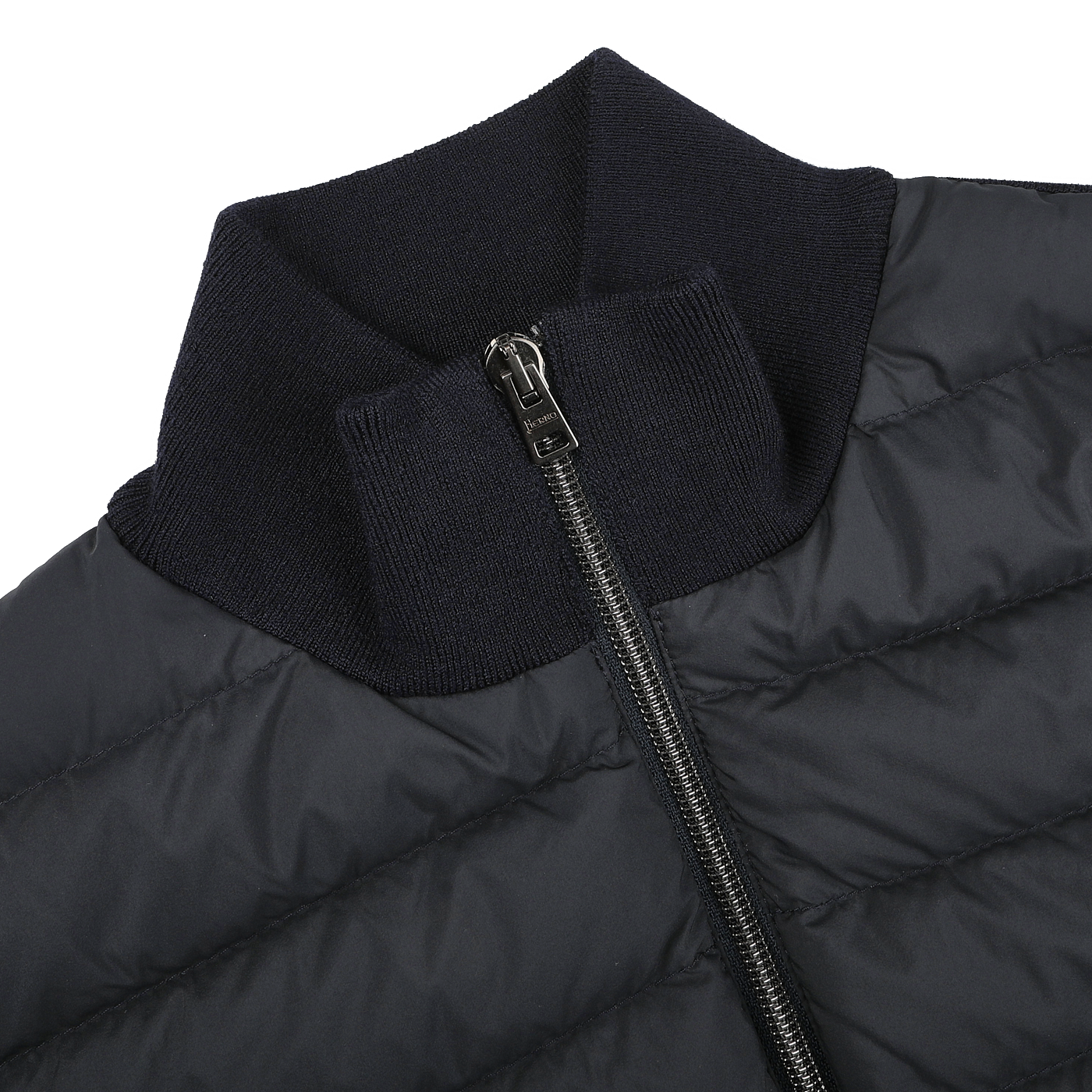 A close-up of a navy blue padded jacket from Herno, crafted from wool, silk, and nylon with a sleek design, high ribbed collar, and front zipper.