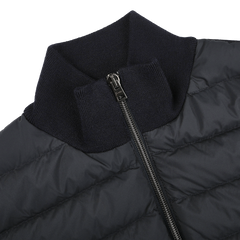 A close-up of a navy blue padded jacket from Herno, crafted from wool, silk, and nylon with a sleek design, high ribbed collar, and front zipper.