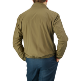 Rear view of a man wearing a Herno olive green white reversible nylon blouson and blue trousers, standing against a neutral gray background.