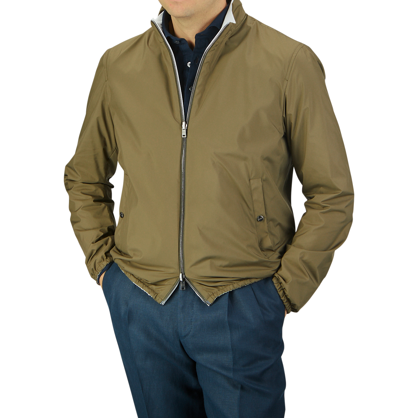 Man wearing a Herno olive green white reversible nylon blouson bomber jacket and blue trousers, hands in pockets, against a gray background. Head cropped from view.