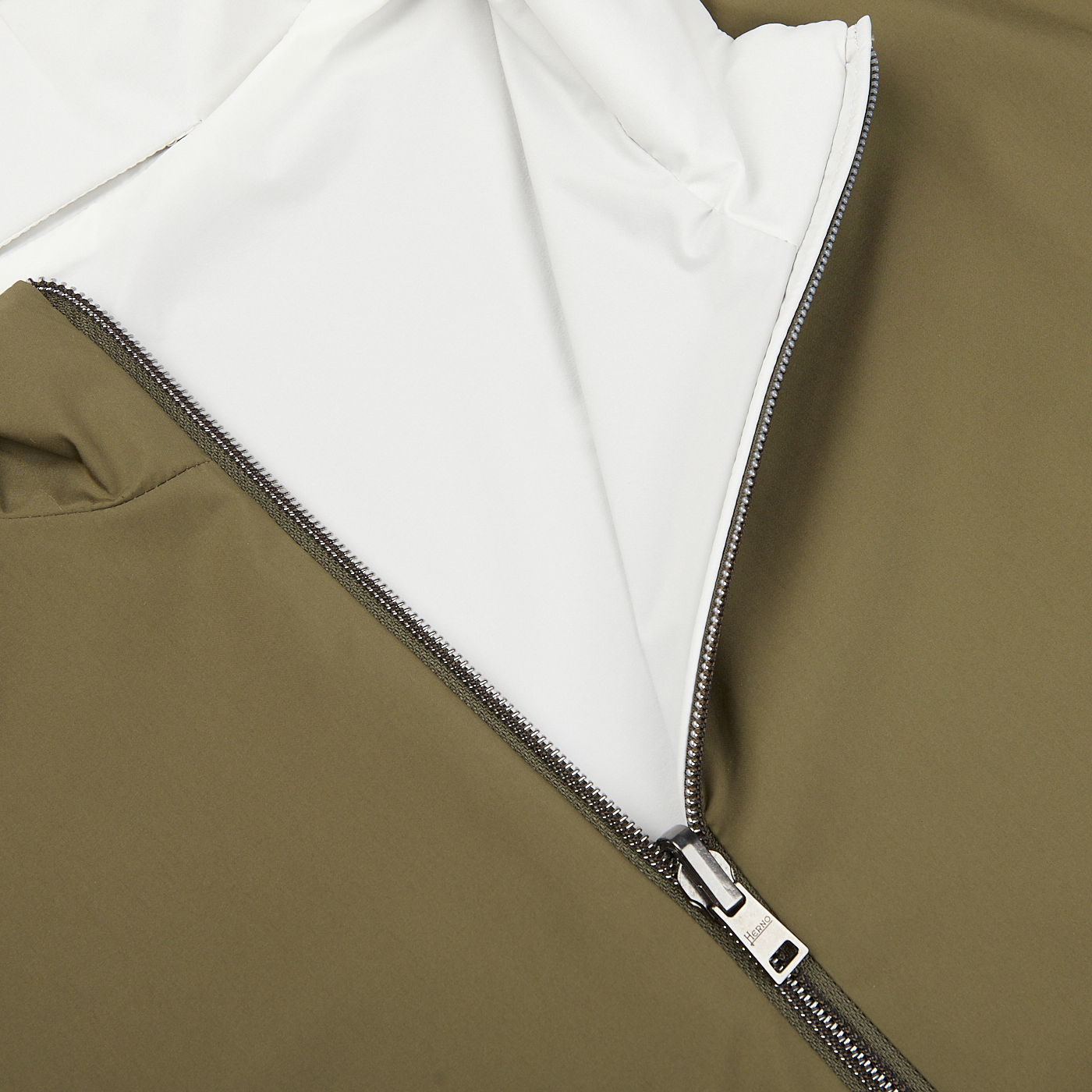 Close-up of a partially zipped Herno Olive Green White Reversible Nylon Blouson with a white interior lining and an olive green, water-resistant nylon exterior.