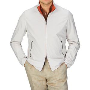 A man wearing an Orange White Reversible Nylon Blouson by Herno made of water-resistant nylon and tan pants.