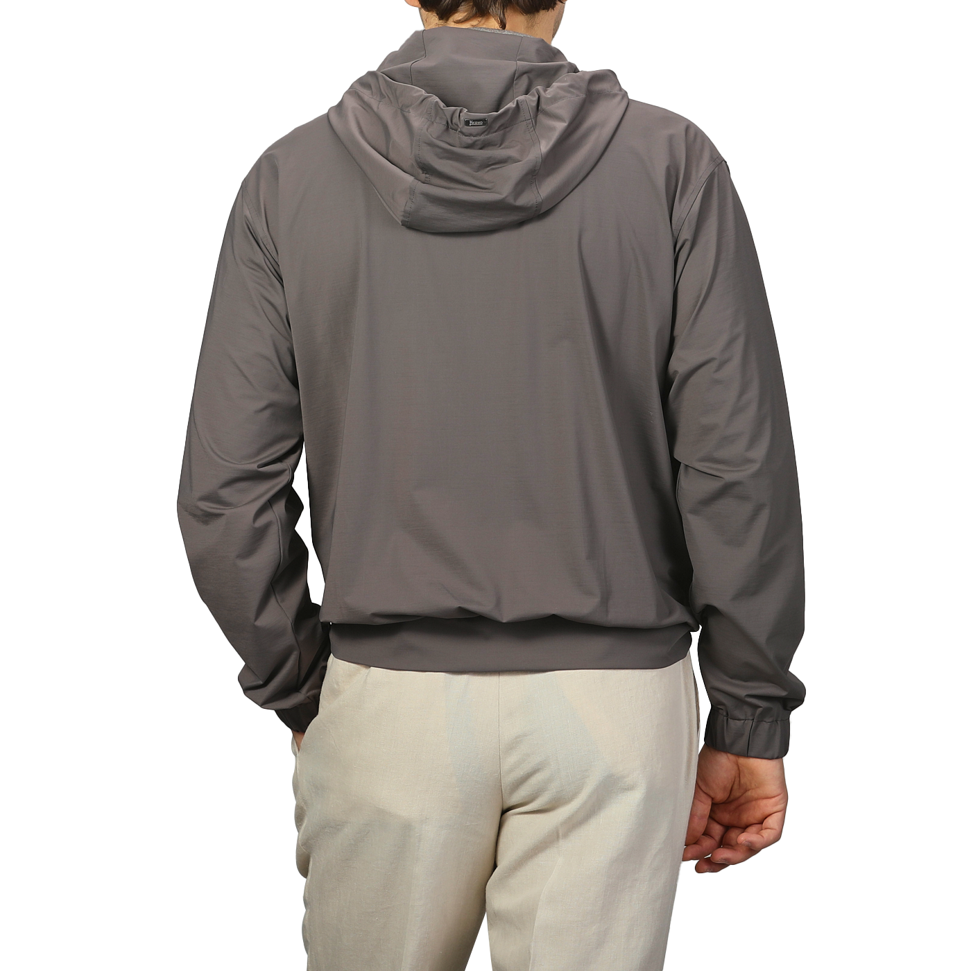 A person wears a Herno Taupe Beige Nylon Jersey Hood Jacket paired with light pants, facing away from the camera against a plain background.