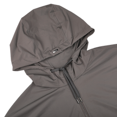 Close-up of a Taupe Beige Nylon Jersey Hood Jacket by Herno, made from lightweight nylon jersey, featuring a zipper and drawstring, shown on a black background.