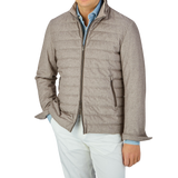 A man sporting a water-repellent Herno Taupe Beige Silk Cashmere Water-Repellent Jacket and slim fit white pants.