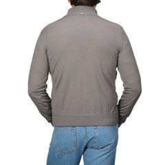 A person is wearing a Herno Taupe Beige Wool Silk Nylon Padded Jacket and blue jeans, facing away.