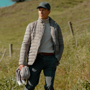 A man in a Herno Taupe Grey Legend Technical Down Jacket walking through a field.