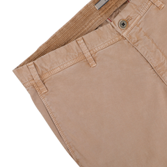 A neatly folded pair of Beige Washed Cotton Gabardine Slim Chinos by Hiltl, featuring a single button and belt loops, rests on a white surface.