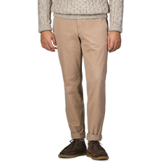 A person wearing a beige cable-knit sweater, Beige Washed Cotton Gabardine Slim Chinos by Hiltl, and dark brown shoes stands against a plain background.