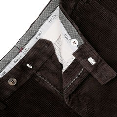 A close-up view of the Brown Cotton Corduroy Regular Fit Chinos shows a zipper and button closure. These chinos, designed for casual wear, have a waistband lined with checked fabric, featuring the "Hiltl" brand name on the inner waistband.