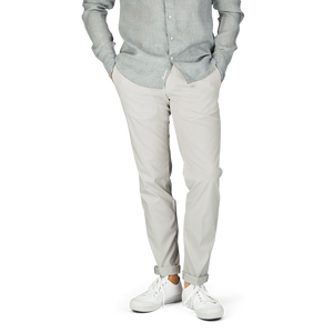 Casual attire – man in a light grey shirt, Hiltl cream beige cotton nylon slim chinos, and white sneakers.