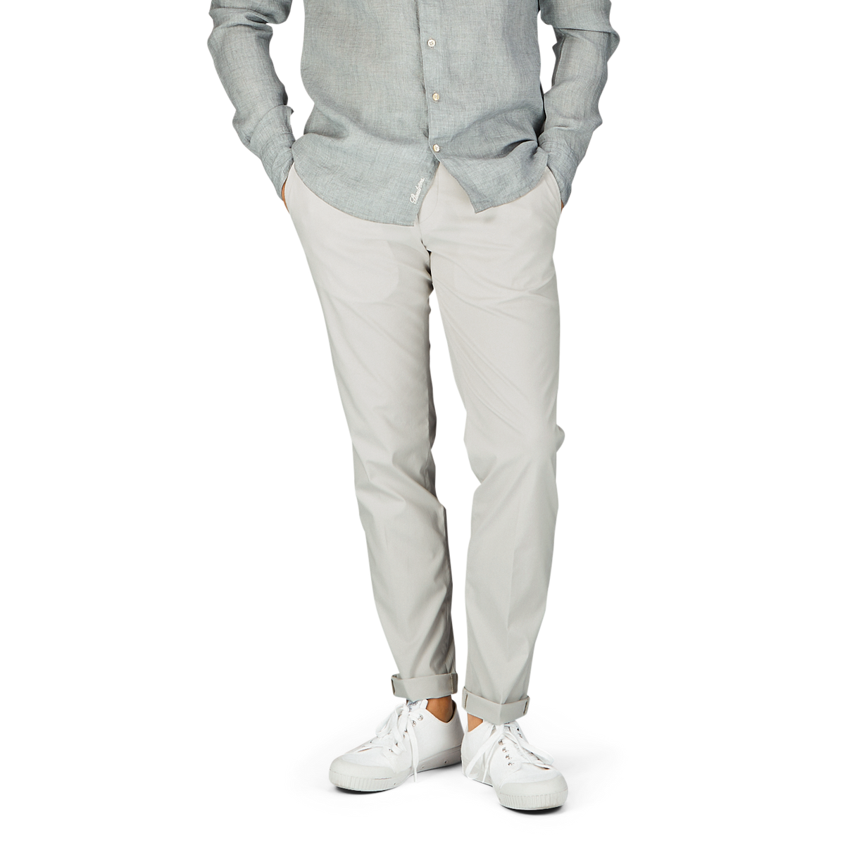 Casual attire – man in a light grey shirt, Hiltl cream beige cotton nylon slim chinos, and white sneakers.