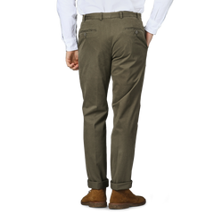 Person wearing Hiltl Dark Green Cotton Stretch Regular Fit Chinos, a white shirt, and brown shoes, facing away.