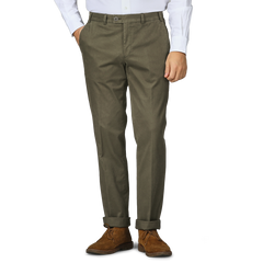 A person wearing Hiltl's Dark Green Cotton Stretch Regular Fit Chinos, a white shirt, and brown suede shoes.