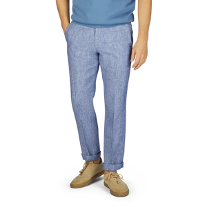 A man wearing light blue washed linen regular fit chinos from Hiltl and beige sneakers stands against a gray backdrop, with only the lower half of his body visible from the waist down.