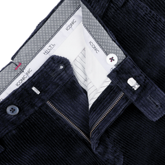 Close-up of navy blue cotton corduroy chinos with visible zipper and button fastenings, showcasing the inner waistband adorned with Hiltl's "Iconic" label patterns. These regular fit chinos provide a classic touch to any ensemble.