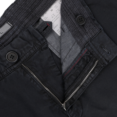 Close-up of navy, slim-fit chinos by Hiltl featuring an open zipper and two visible buttons on the waistband. A clothing label is present inside the washed cotton gabardine waistband.