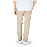Man standing in a white t-shirt, Hiltl sand beige cotton nylon slim chinos, and white sneakers.