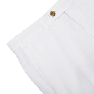 Close-up of a Hiltl white washed linen regular fit chinos waistband with a button closure on a gray background.