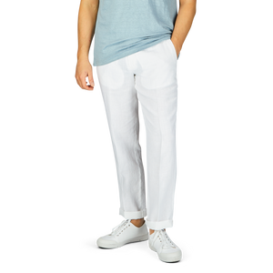 A person wearing a light blue t-shirt, Hiltl's White Washed Linen Regular Fit Chinos, and white sneakers standing against a grey background.