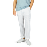 A person wearing a light blue t-shirt, Hiltl's White Washed Linen Regular Fit Chinos, and white sneakers standing against a grey background.