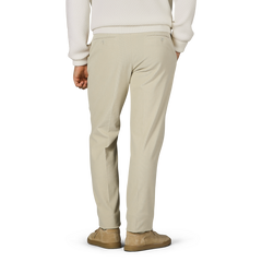 Person wearing Incotex Beige Cotton Corduroy High Comfort Chinos, a white sweater, and matching beige shoes is shown from the back, standing against a plain background.