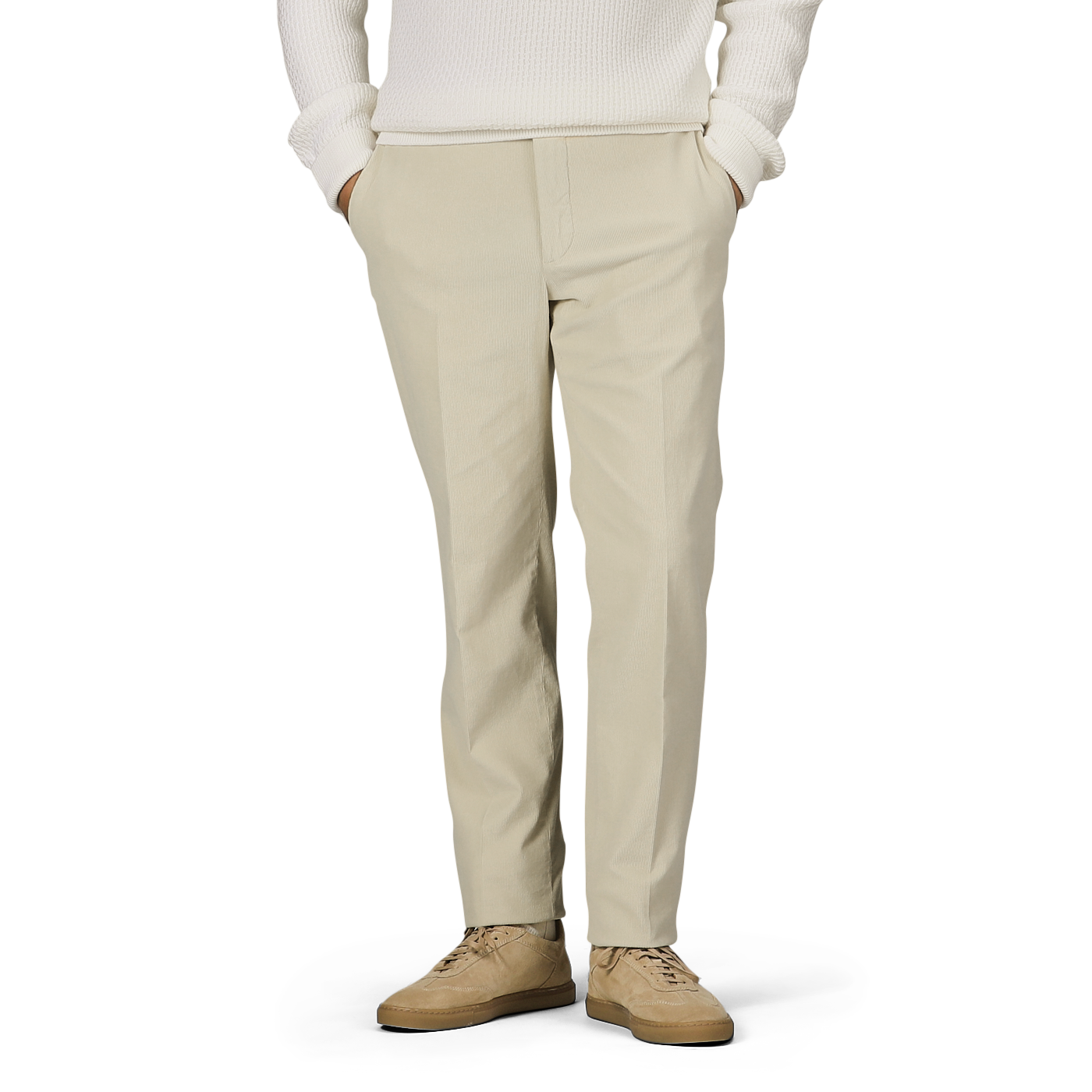 A person wearing Incotex Beige Cotton Corduroy High Comfort Chinos, a white sweater, and beige shoes stands with hands in pockets against a neutral background.