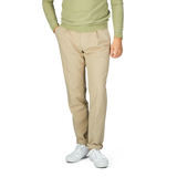 A man wearing a green sweater and Incotex Beige Cotton Stretch Pleated Chinos.