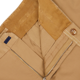 Close-up of a beige Incotex chinos showing details of a zipper, button, and various textiles including corduroy and smooth fabric.