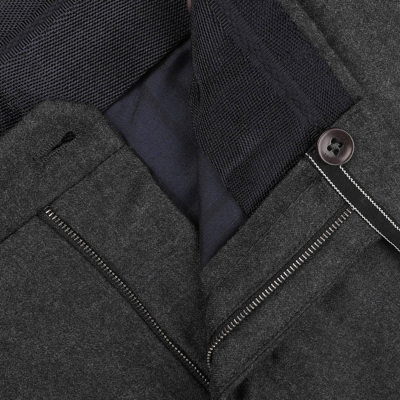 Close-up of a dark grey jacket's zipper and button details, perfectly complementing the Charcoal Grey Wool Flannel Slim Trousers by Incotex.