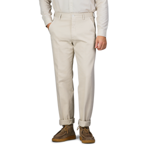 A person wearing Cream Beige Cotton Stretch Model 8 Chinos by Incotex, paired with a white shirt and brown shoes, stands with hands in pockets.