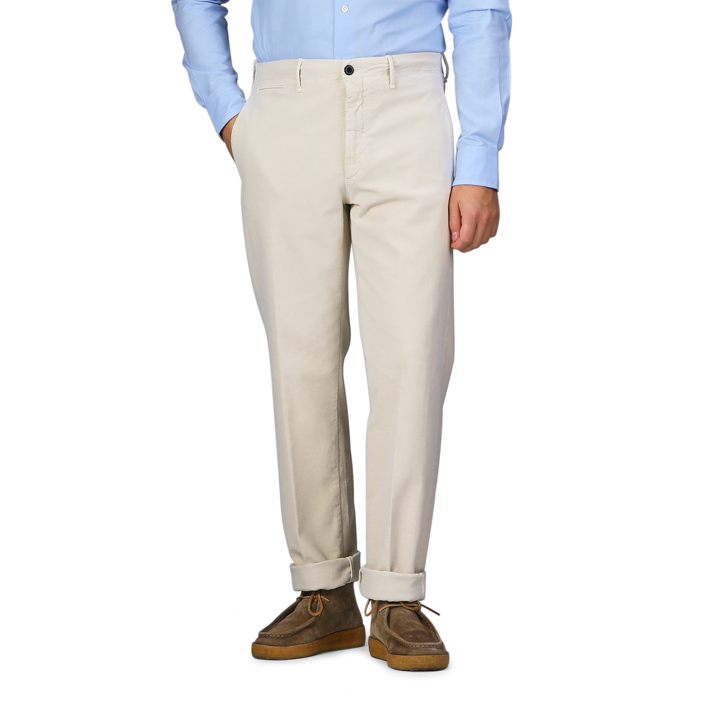 A person wearing Incotex Cream Beige Cotton Moleskin Slacks Chinos, a light blue shirt, and brown shoes stands with one hand in their pocket.