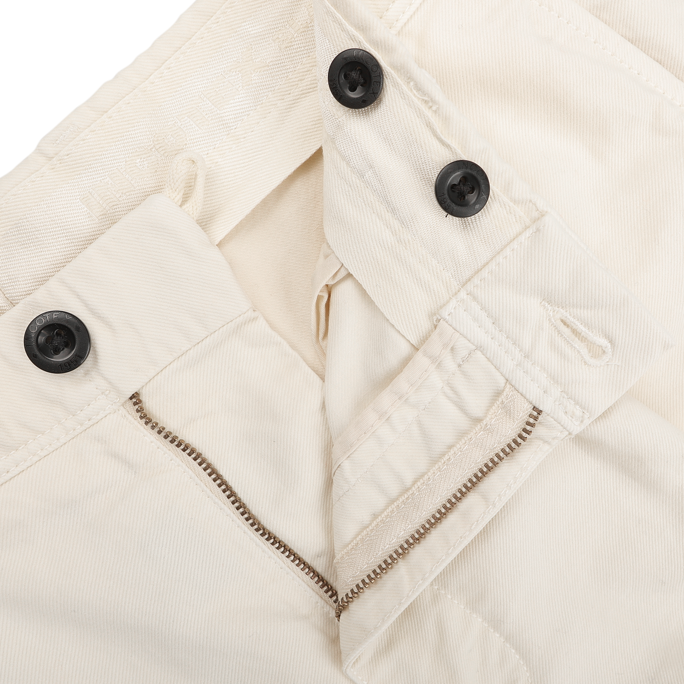 Close-up of the Cream White Cotton Twill Pleated Chinos by Incotex, featuring a slim fit design with black buttons and a partially open metal zipper.