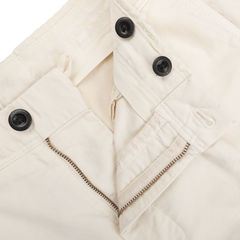 Close-up of the Cream White Cotton Twill Pleated Chinos by Incotex, featuring a slim fit design with black buttons and a partially open metal zipper.