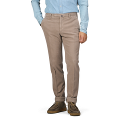 A person in a light blue shirt and Dark Beige Cotton Moleskin Model 30 Chinos by Incotex, hands in pockets, stands against a plain background.