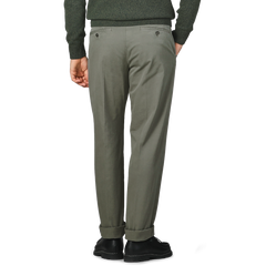 A person wearing Dark Green Cotton Stretch Model 8 Chinos by Incotex and a dark sweater stands with their back turned, hands in pockets, and is wearing black shoes.