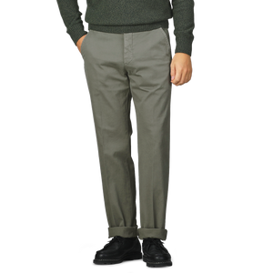 A person dressed in Incotex's Dark Green Cotton Stretch Model 8 Chinos, regular fit gray cotton twill chinos, and black shoes stands with hands in pockets on a plain background.