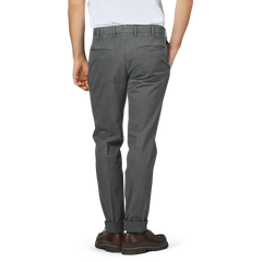 A person wearing Incotex's Dark Grey Cotton Stretch Model 30 Chinos, expertly crafted from cotton twill in a slim fit, paired with brown shoes, viewed from the back.