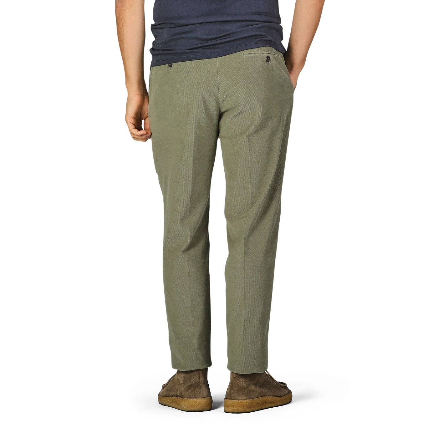 A person stands wearing Incotex Green Cotton Corduroy High Comfort Chinos, a dark blue shirt, and brown shoes. The individual is facing away from the camera with hands in the chinos' pockets.