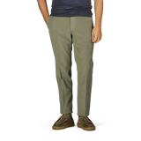 A person wearing Incotex Green Cotton Corduroy High Comfort Chinos, a dark shirt, and brown shoes stands with hands in pockets.