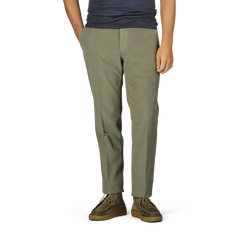 A person wearing Incotex Green Cotton Corduroy High Comfort Chinos, a dark shirt, and brown shoes stands with hands in pockets.