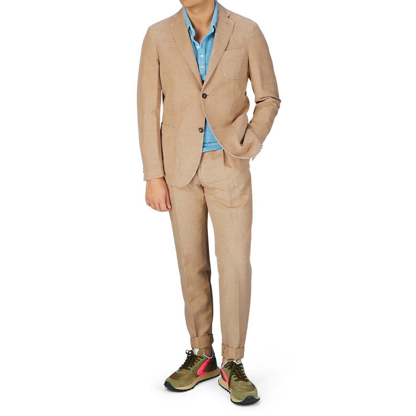 A man wearing a Slowear Light Beige Washed Chinolino Suit with medium-rise trousers, a blue shirt, and colorful sneakers.