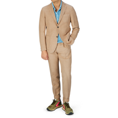 A man wearing a Slowear Light Beige Washed Chinolino Suit with medium-rise trousers, a blue shirt, and colorful sneakers.