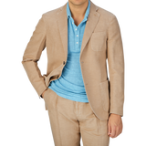 A person wearing a Slowear Light Beige Washed Chinolino Suit jacket over a light blue t-shirt, with matching medium-rise Slowear Light Beige Washed Chinolino Suit trousers.