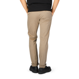The back view of a man wearing light brown cotton stretch slacks chinos by Incotex.