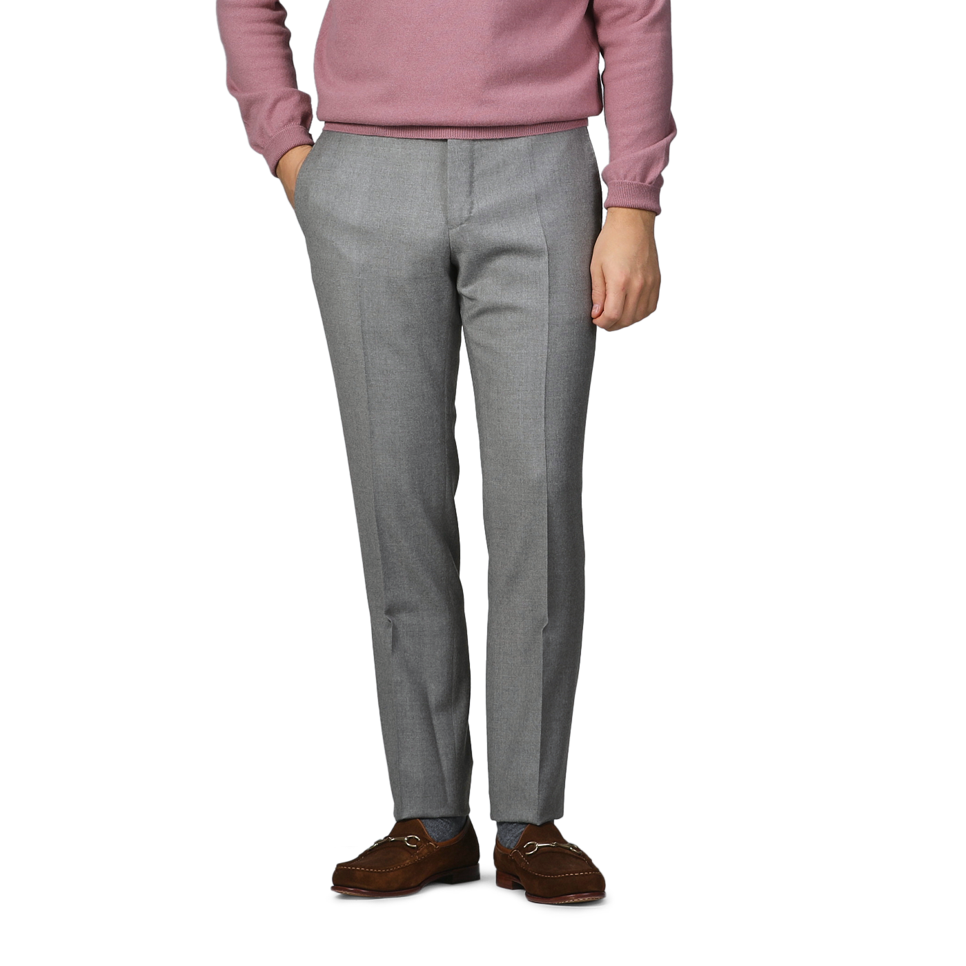 A person wearing a pink sweater, Light Grey Wool Flannel Slim Trousers by Incotex, and brown leather shoes stands with hands in pockets against a plain background.