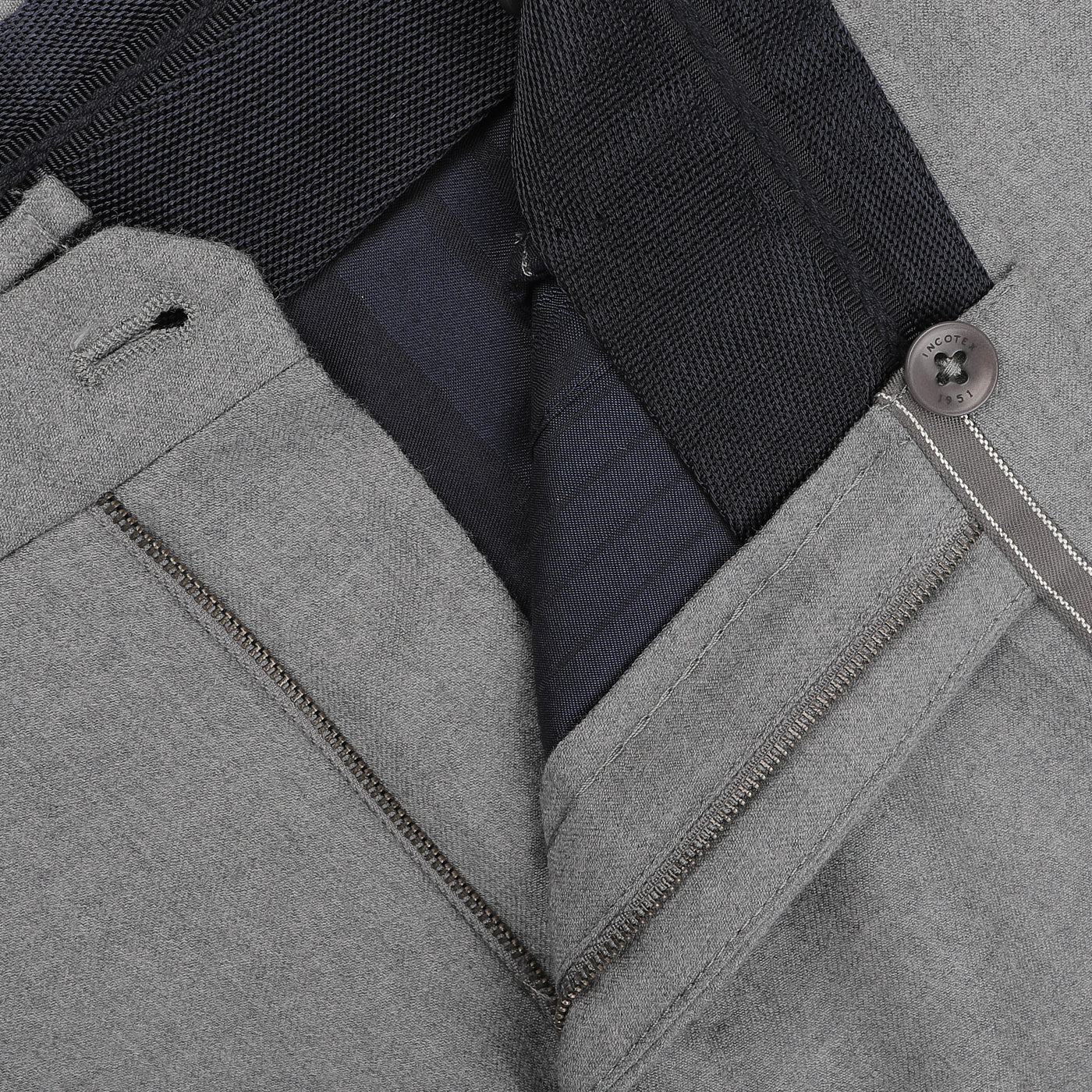 Close-up of the Light Grey Wool Flannel Slim Trousers by Incotex, showcasing the undone zipper that reveals the buttoned waistband and inner black lining. These trousers offer a sleek, modern look combined with exceptional comfort.