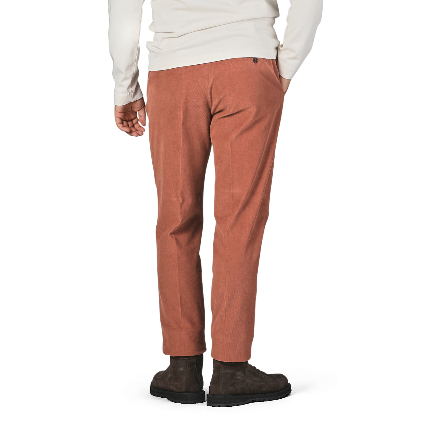 A person in a white long-sleeve shirt and Incotex Muted Orange Cotton Corduroy High Comfort Chinos is standing with one hand in their pocket, showing the back view. They are wearing dark brown shoes.