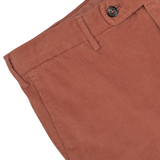 Close-up of a pair of Muted Orange Cotton Corduroy High Comfort Chinos by Incotex, showing the waistband, button, belt loops, and pocket detail.